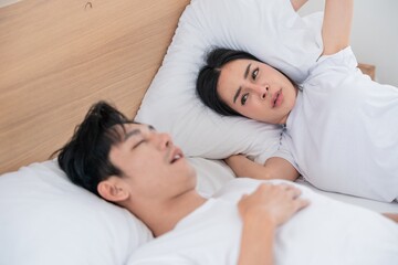 Couple in bed experiencing discomfort during sleep in a bright room