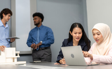 Obraz premium Professional business discussion between two female colleagues using laptop in modern office, teamwork collaboration, diverse workplace, technology in business, professional attire, strategic planning