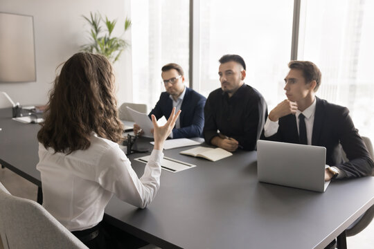 Unfair barrier. Back view young lady business professional compete for opening for her dream job but feel pressure bias prejudice on interview with male recruiters team having gender based stereotypes
