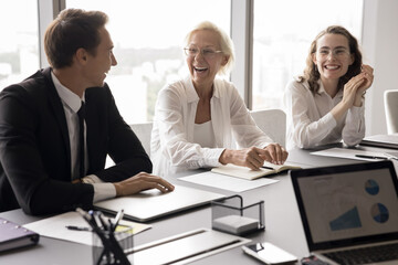 Positive work environment. Laughing candid diverse age corporate workers group having fun on brainstorm session discussion at office meeting room engaged in friendly collaboration enjoy relaxed moment