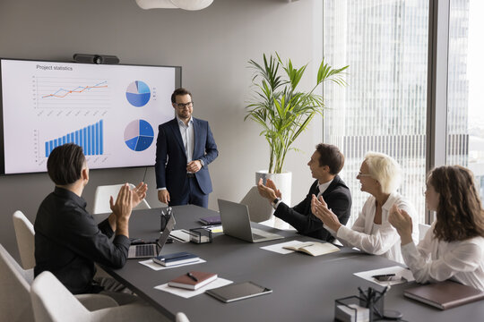 Recognition of achievement. Smiling businesspeople group office workers colleagues meet at boardroom table clap hands applause project manager celebrate success after presentation of statistic results