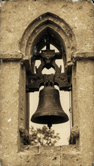 Obraz premium Vintage black and white photo of a cast-iron church bell in a stone arch. Sepia, aging effect, scuffs. The atmosphere of the past, retro style, historical setting.