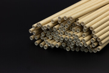 Paper straws on black background, Paper straws, Accessories for drinking outdoors, Ecology recycling eco friendly, Eco friendly reusable paper straws, Kraft paper straw for drinking coffee or tea.