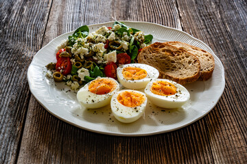 Delicious breakfast - boiled eggs with vegetables and feta cheese served on wooden table

