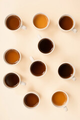 many mugs with different coffee on a pastel table top