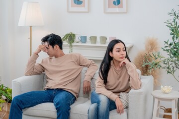 Couple sitting in silence on a couch during a tense moment in a cozy living room setting