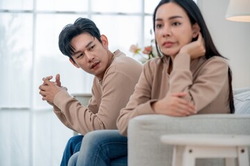 Couple sitting in a modern living room during a tense conversation in soft afternoon light