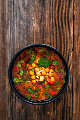 Fresh vegetable soup with chickpea on wooden table
