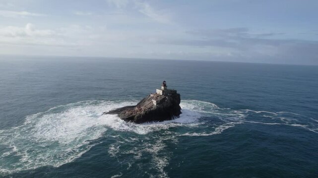 Aerial: Tillamook Rock Light lighthouse with waves crashing during the day in North Pacific Ocean, northern Oregon Coast, USA, parallax drone shot