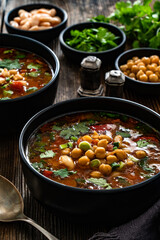 Fresh vegetable soup with chickpea on wooden table
