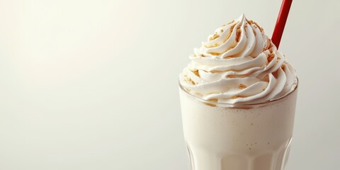 Creamy milkshake topped with whipped cream in a glass served with a red straw in a cozy setting