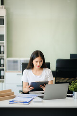 Confident business expert attractive smiling young woman typing laptop and holding digital tablet