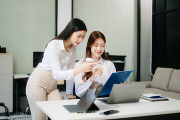 Obraz premium Asian business colleague business presents and explains and using laptop and tablet. Teamwork, financial marketing team,