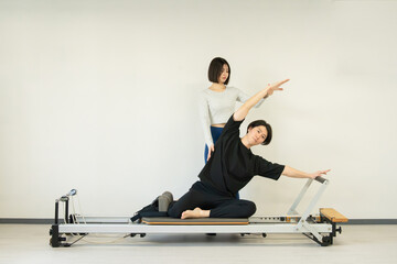 日本人男性がキャデラックを使って行うピラティスエクササイズ