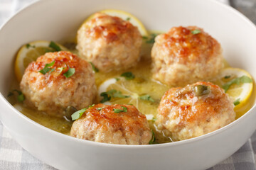 Italian chicken meatballs with picatta sauce consisting of capers, butter, lemons, and wine close-up in a plate. Horizontal