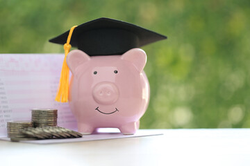 Graduation hat on piggy and stack of coins money on natural green background, Saving money for education concept