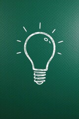 A Hand-Drawn Lightbulb Symbol on a Green Surface Representing a Brilliant Idea