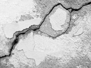 Big winding ascending crack on an gray concrete wall with traces of paint. Wide and deep diagonally fault. Black and white photo. Close-up. Copy space for text. Selective focus.