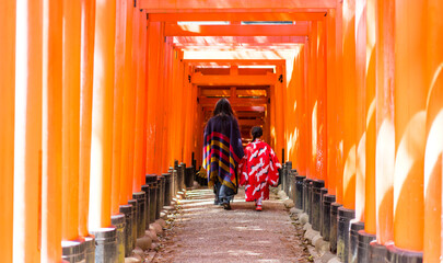 Mom and daughter walking under red gate in Kyoto