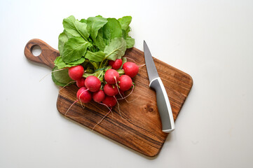 Preparing healthy food or a salad. Radish and knife on chopping board on table. 