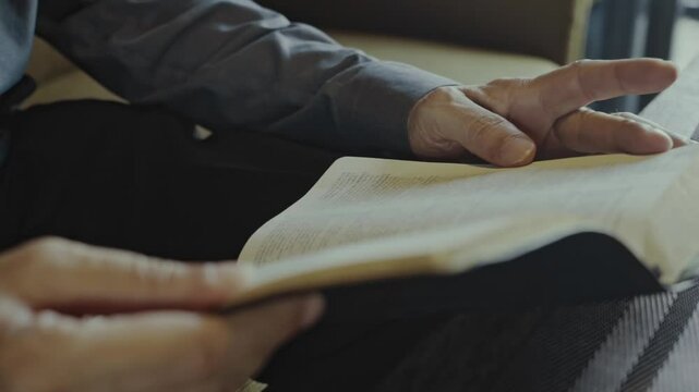 close up of hands of white businessman Reading the Bible in a Dimly Lit Living Room