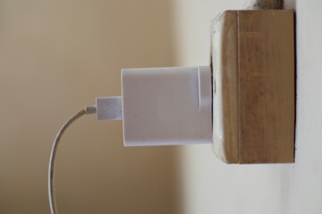 Phone charger connected to a weathered outlet, symbolizing energy connectivity and power reliance