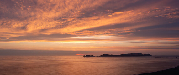 Aerial view to Vibrant sunset illuminating clouds over calm ocean and islands