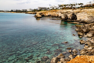 The clearest turquoise water near the rocky shore of the resort Ayia Napa. Large boulders are...