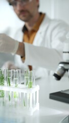 Man scientist wearing a lab coat, white gloves and protective glasses, is dripping liquid from a...