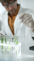 Man scientist wearing a lab coat, white gloves and protective glasses, is dripping liquid from a...