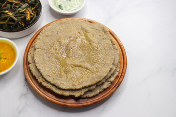 Roti and Sabzi. Indian vegetarian Thali includes bhindi fry, yellow daal tadka, cucumber raita, and jawari or Jowar bhakri. Indian food is served in a plate or thali. Copy Space. healthy Veg Thali.