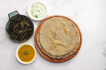 Roti and Sabzi. Indian vegetarian Thali includes bhindi fry, yellow daal tadka, cucumber raita, and jawari or Jowar bhakri. Indian food is served in a plate or thali. Copy Space. healthy Veg Thali.