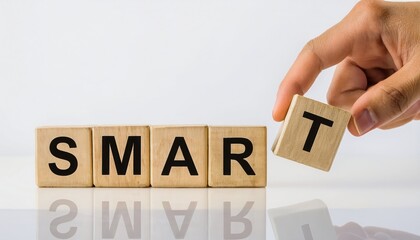 A hand placing a wooden block to form the word SMART on a reflective surface.