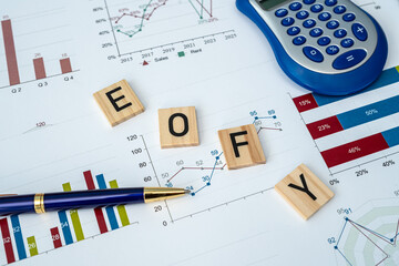 Business concept with word EOFY on wooden cubes and chart pen calculator