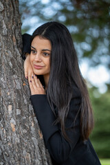 Young businesswoman relaxing in the park leaning against a tree
