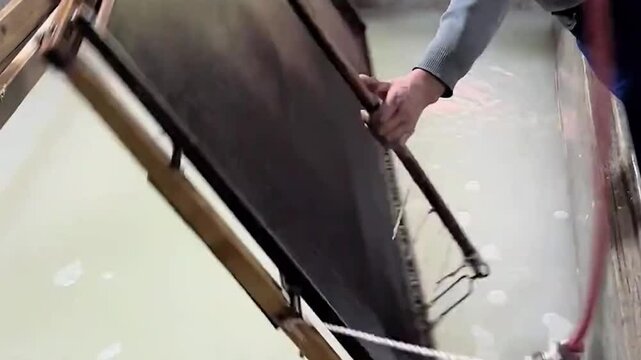 A workshop worker demonstrates traditional Chinese papermaking techniques