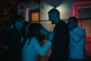 A lively gathering of friends enjoying an evening celebration in a relaxed and vibrant home atmosphere with music and fun interactions.