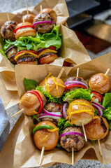 Bite-Size Mini Burgers on Skewers Served on Brown Paper for a Delicious Takeaway Snack