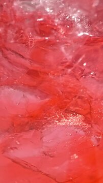 slow motion of ice cubes in cold red cocktail drink. beverage closeup, macro