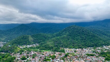 Fototapeta premium Linda vista aerea com drone sobre o mar com montanhas e cidade ao fundo com cores vibrantes.