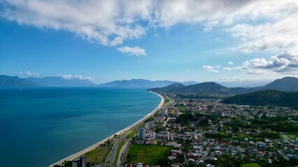 Linda vista aerea com drone sobre o mar com montanhas e cidade ao fundo com cores vibrantes.