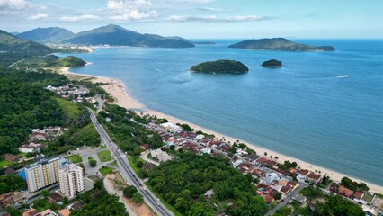 Fototapeta premium Linda vista aerea com drone sobre o mar com montanhas e cidade ao fundo com cores vibrantes.