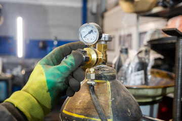Gas Cylinder Valve Adjustment. A worker in a dirty glove adjusts a gas cylinder valve with a...