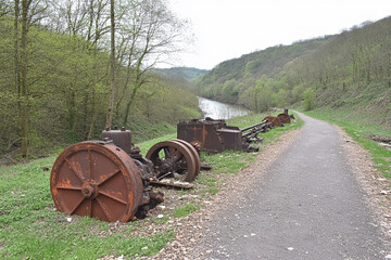 Pathway leading through forest with decayed industrial equipment along the side