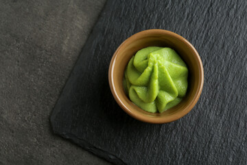 Hot wasabi paste in bowl on grey textured table, top view. Space for text