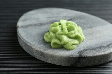 Marble board with hot wasabi paste on black textured table, closeup
