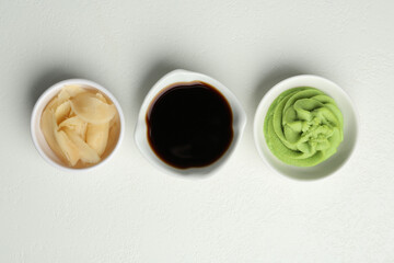 Fototapeta premium Hot wasabi paste, soy sauce and ginger on light textured table, flat lay