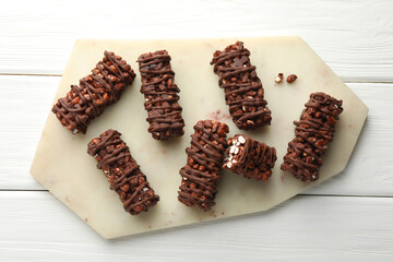 Delicious chocolate puffed rice bars on white wooden table, top view