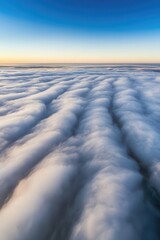 Clouds at sunrise with vibrant sky and textured patterns, aerial view of fluffy cloud layer, peaceful natural scenery, serene skies, atmospheric landscape.