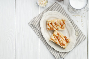 Delicious caramel puffed rice bars served on white wooden table, flat lay. Space for text